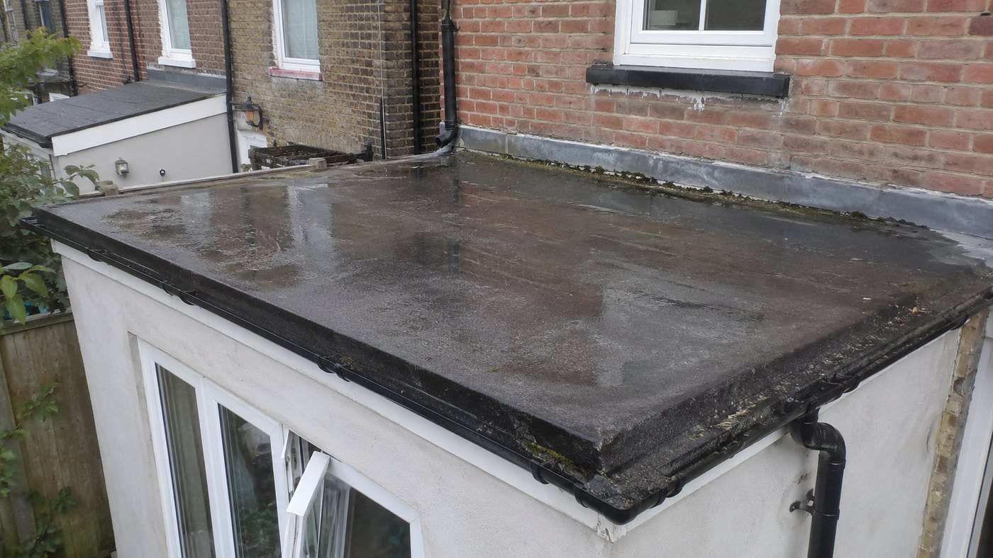 Wet flat roof on a house extension, showing puddling and wall junctions.